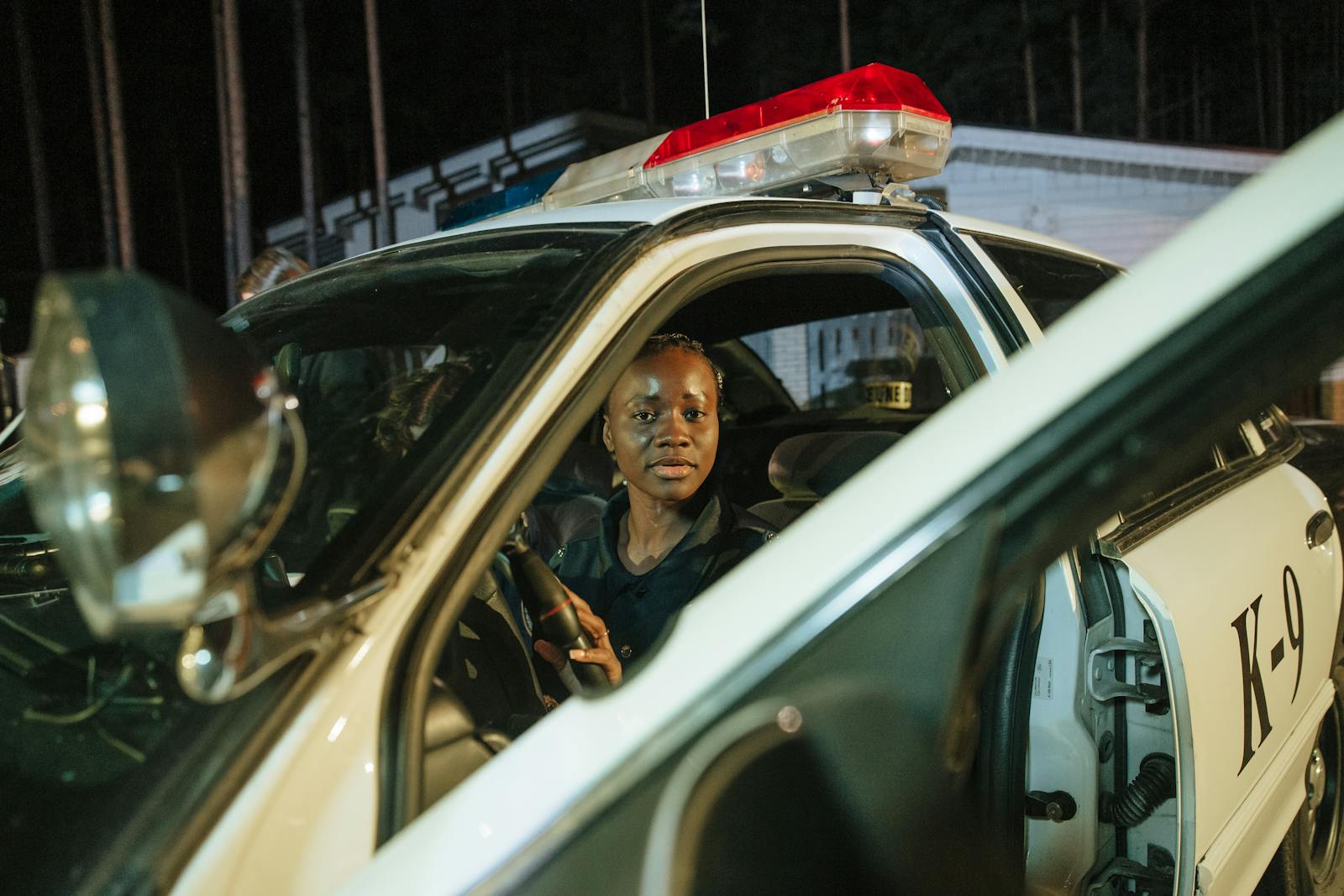 A female police officer sits in a K-9 car during nighttime duties.