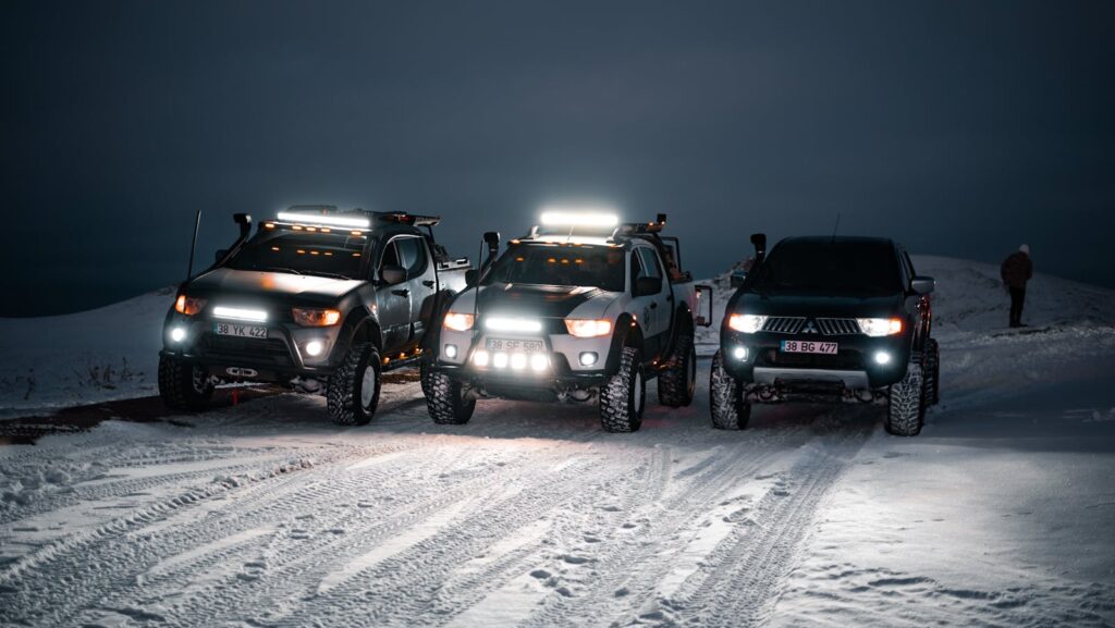 Three rugged off-road vehicles on a snowy road at night, showcasing adventure and exploration.