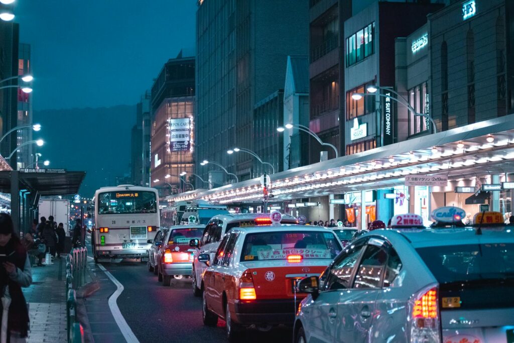 Vibrant city street scene with heavy traffic and illuminated buildings at night.
