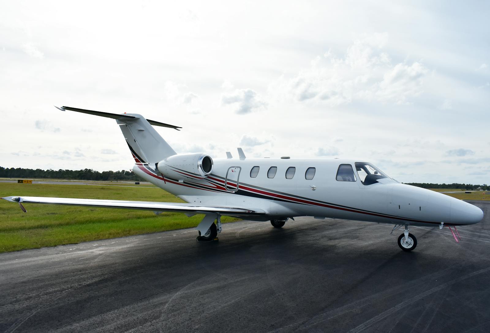 Sleek private jet on an airport runway set against a bright sky, ready for takeoff.