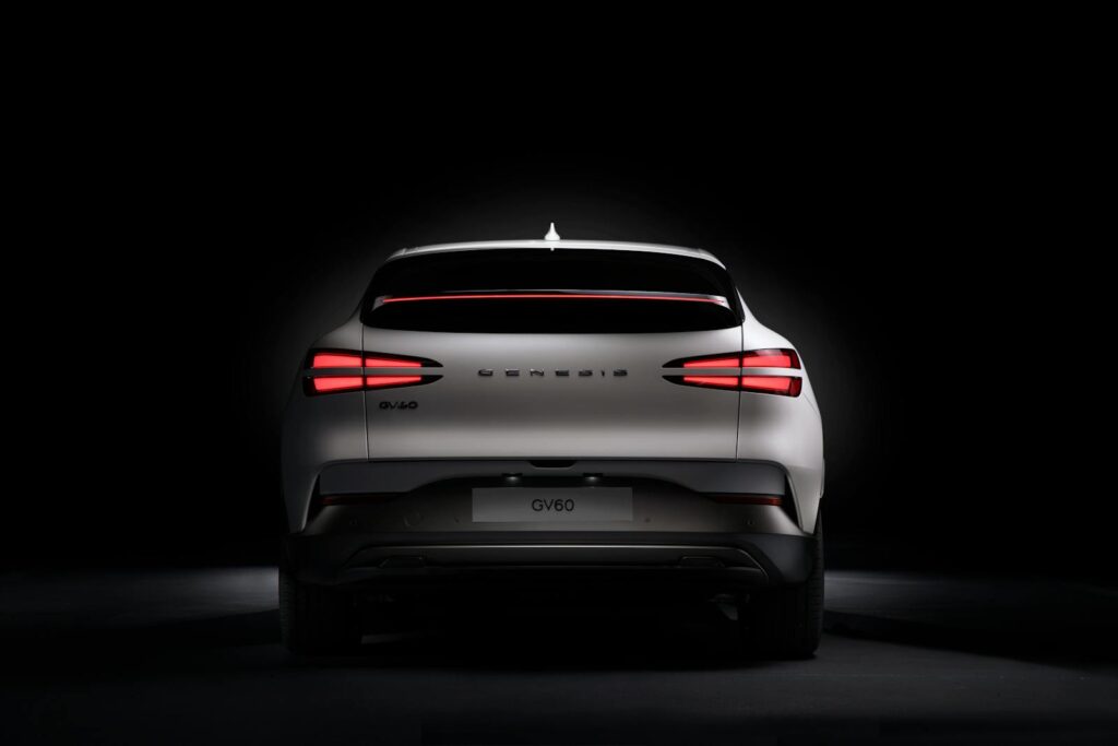 Rear view of a white Genesis GV60 electric car showcasing its distinctive rear lamp design.