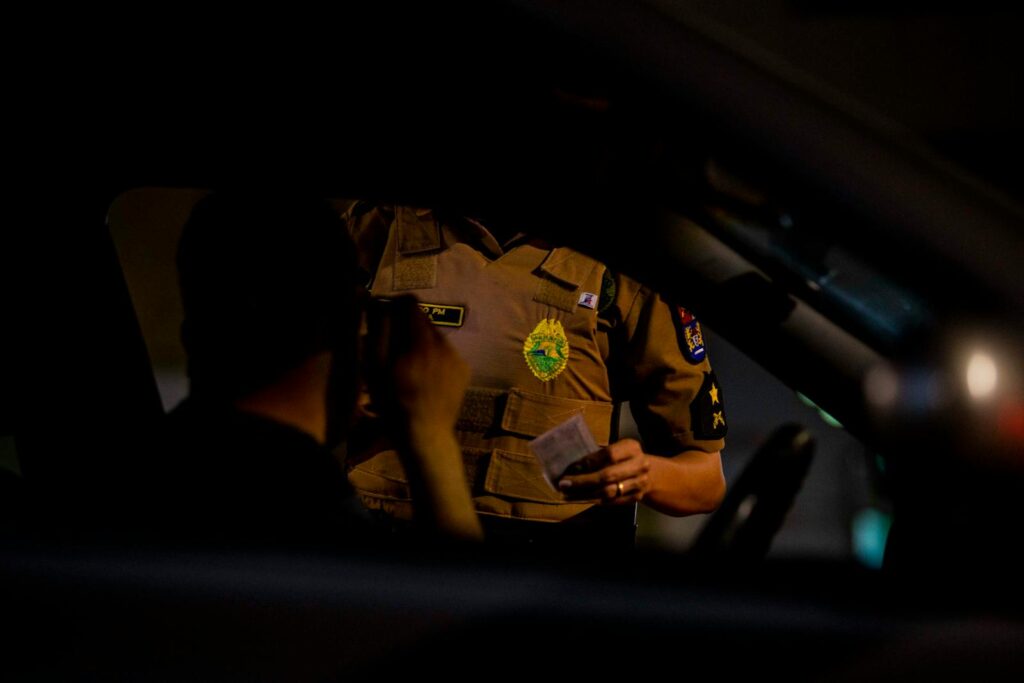 A police officer conducting a car inspection at night in Londrina, PR, Brazil.