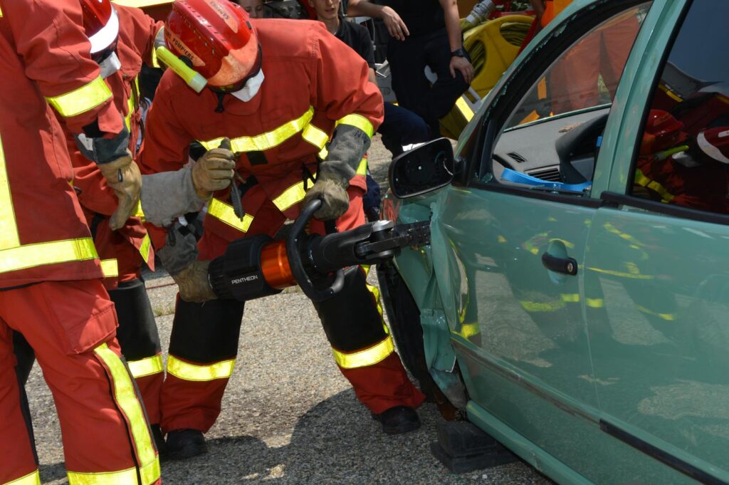 Firefighters demonstrate rescue techniques using a hydraulic cutter at a car crash practice session.