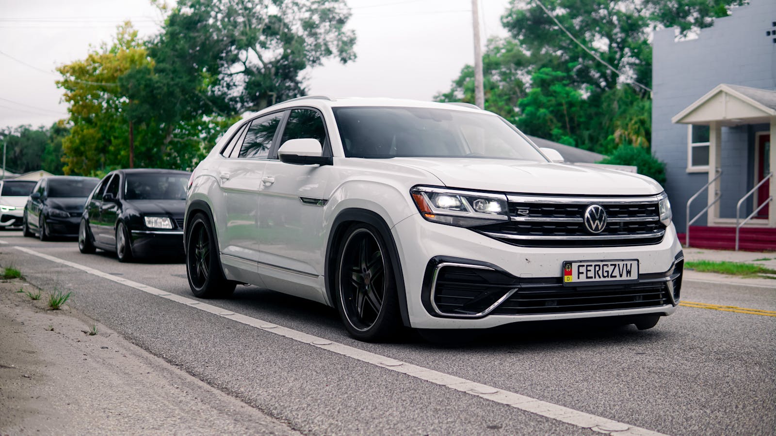 White Volkswagen Atlas Cross Sport on a city street, showcasing urban transportation.