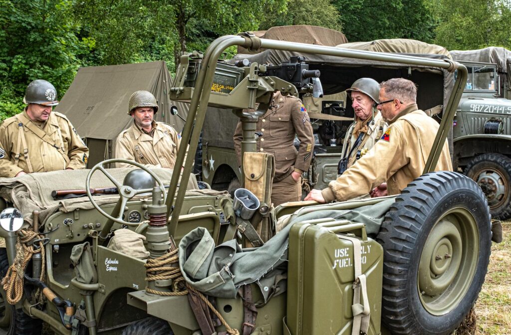 Group of soldiers in vintage military uniforms discussing strategy by jeeps.