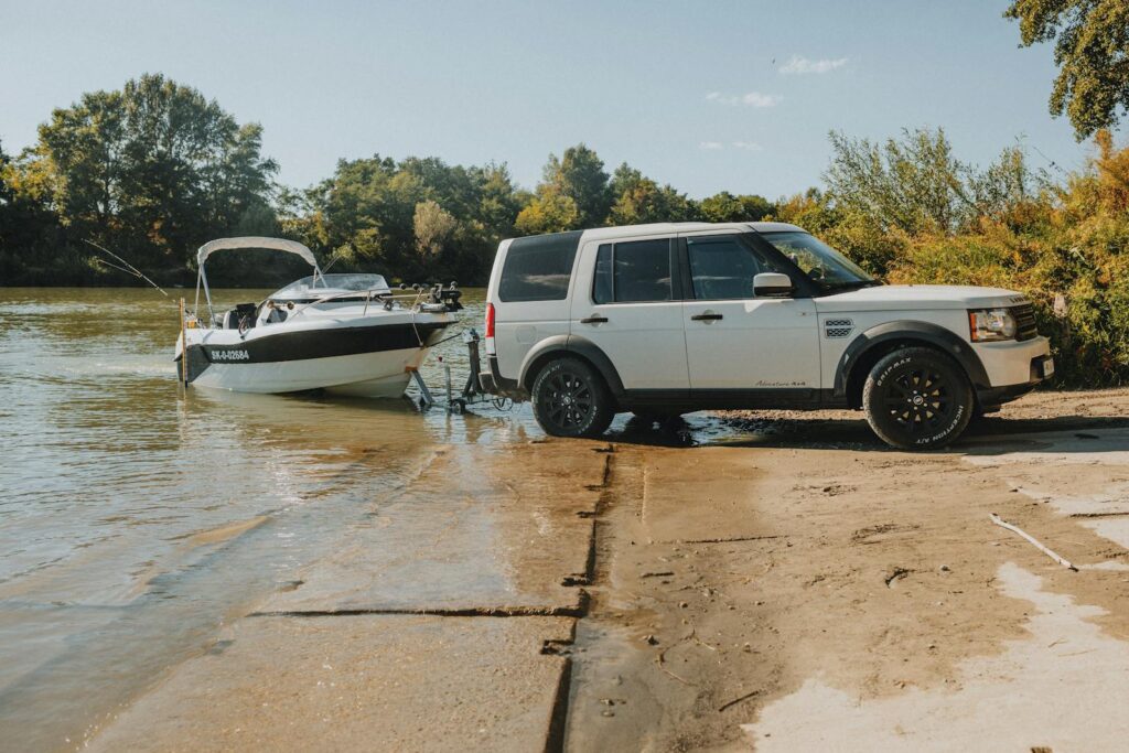 An SUV launching a speedboat into a river on a sunny day, showcasing outdoor adventure.
