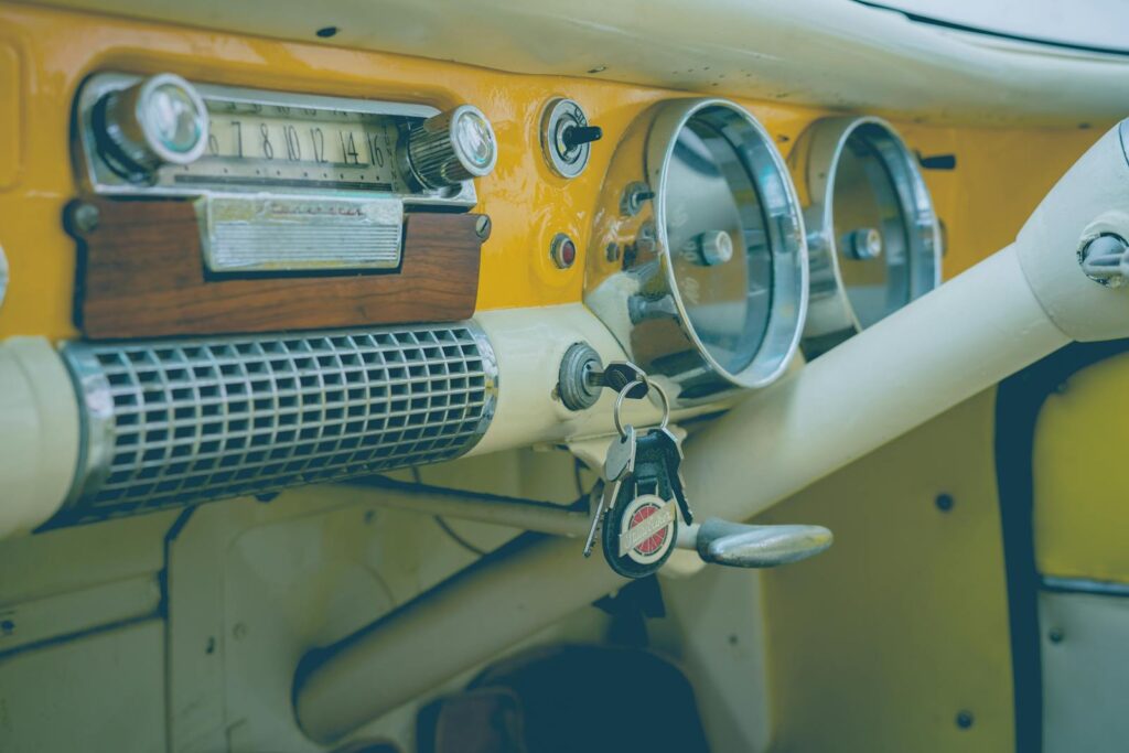 Close-up of a classic vintage car dashboard featuring an analog radio, speedometer, and keys.
