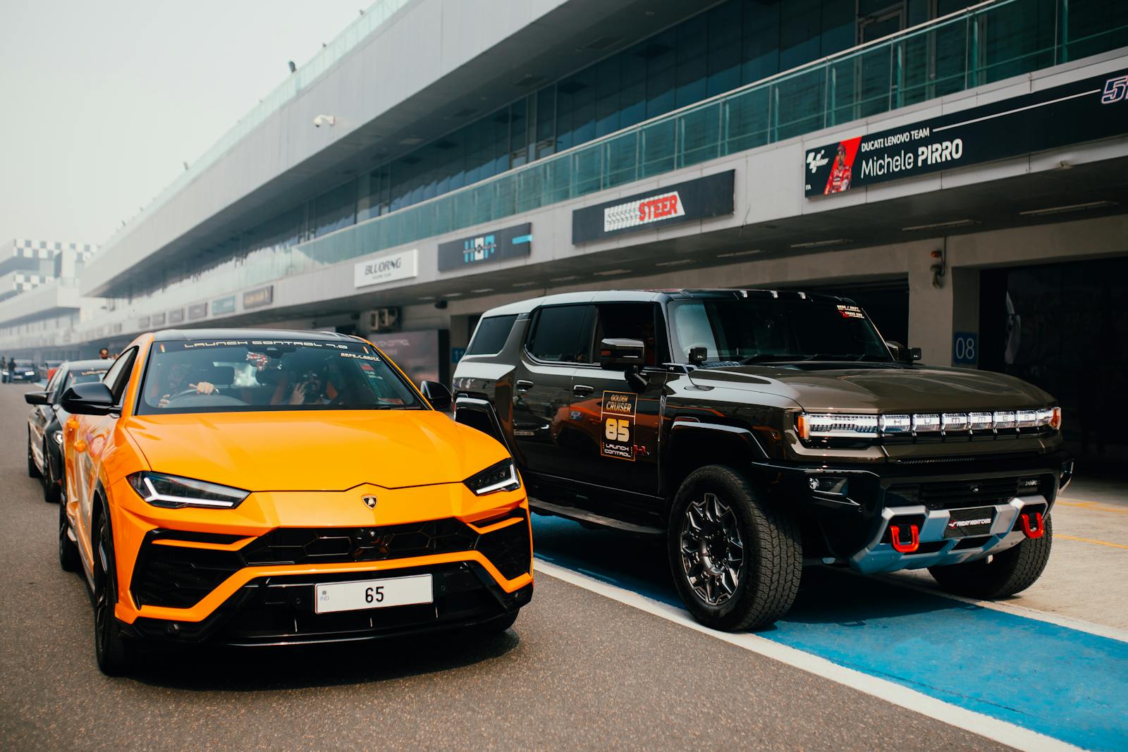 Orange Lamborghini and Black SUV parked on racetrack in Greater Noida, India.