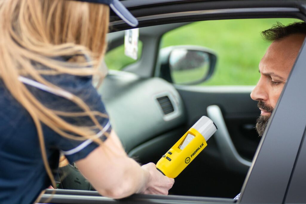 Police officer administering a breathalyzer test to a driver in a car, ensuring road safety.