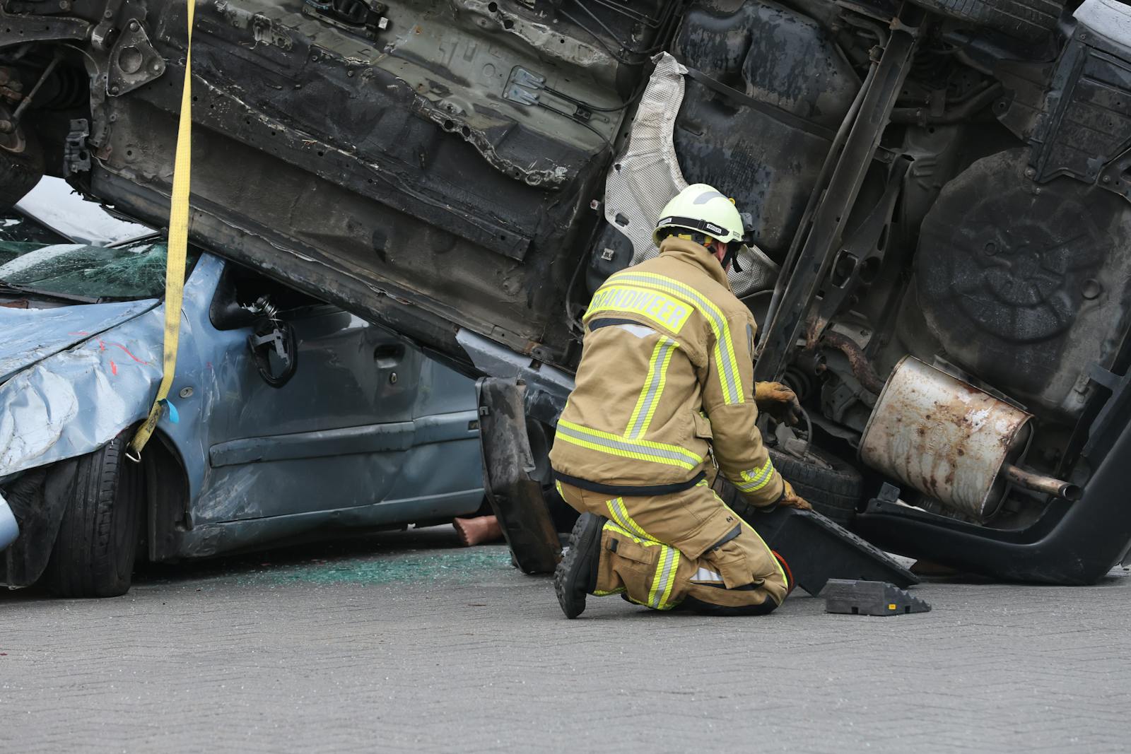 Firefighter in gear assisting at an overturned car crash scene, ensuring safety during the rescue operation.