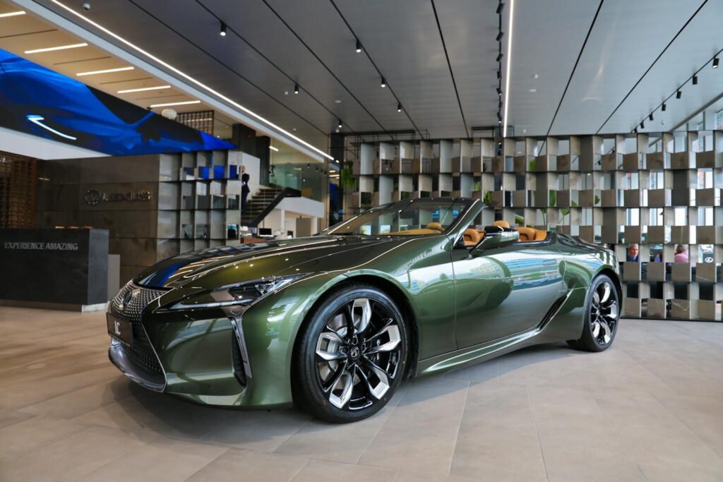 A green luxury convertible displayed in an elegant, modern car showroom with sleek interior design.