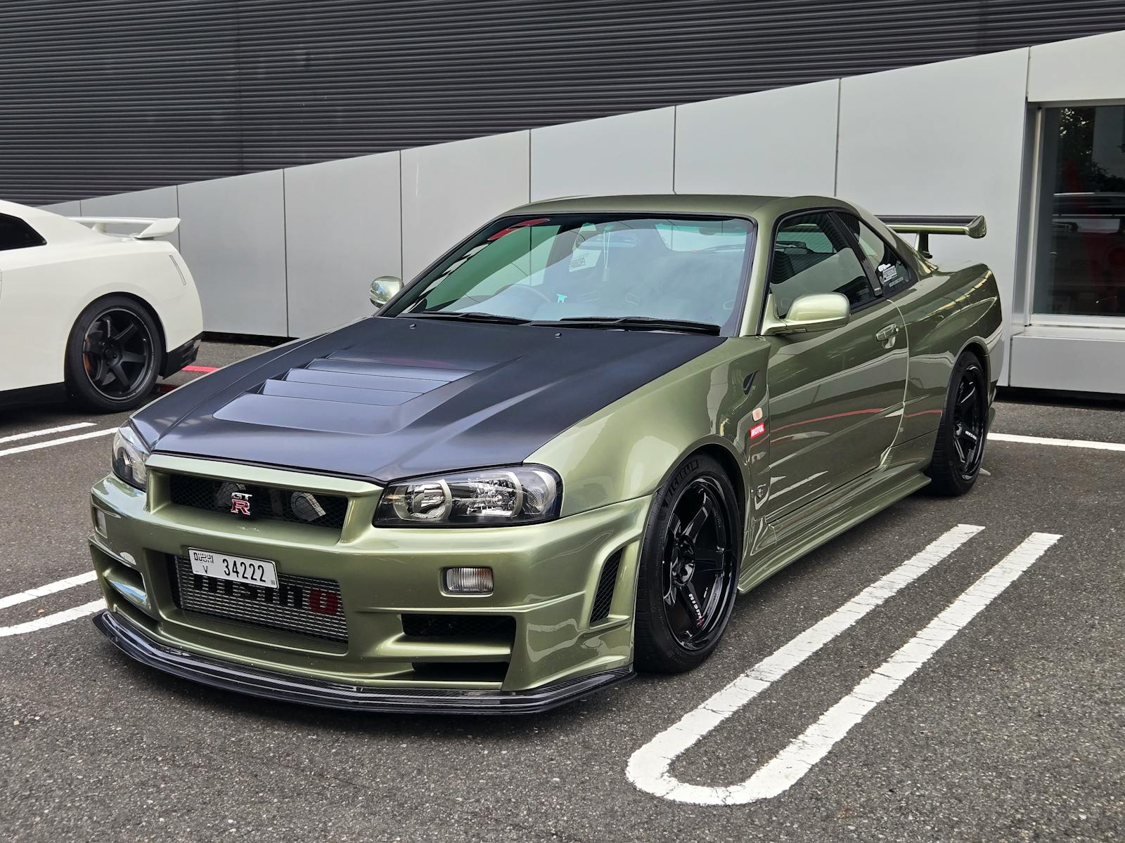 A stylish green Nissan GT-R Skyline R34 parked outdoors in Tokyo, Japan.