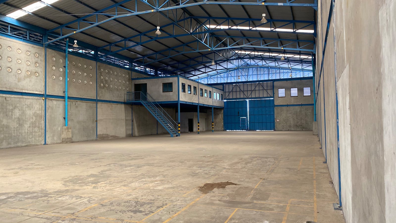 Empty warehouse with blue steel frame and concrete walls in Bangkok.