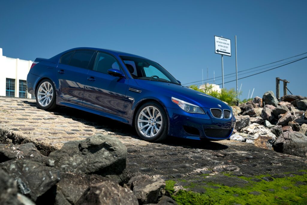 Blue BMW m5 parked on rocky terrain.
