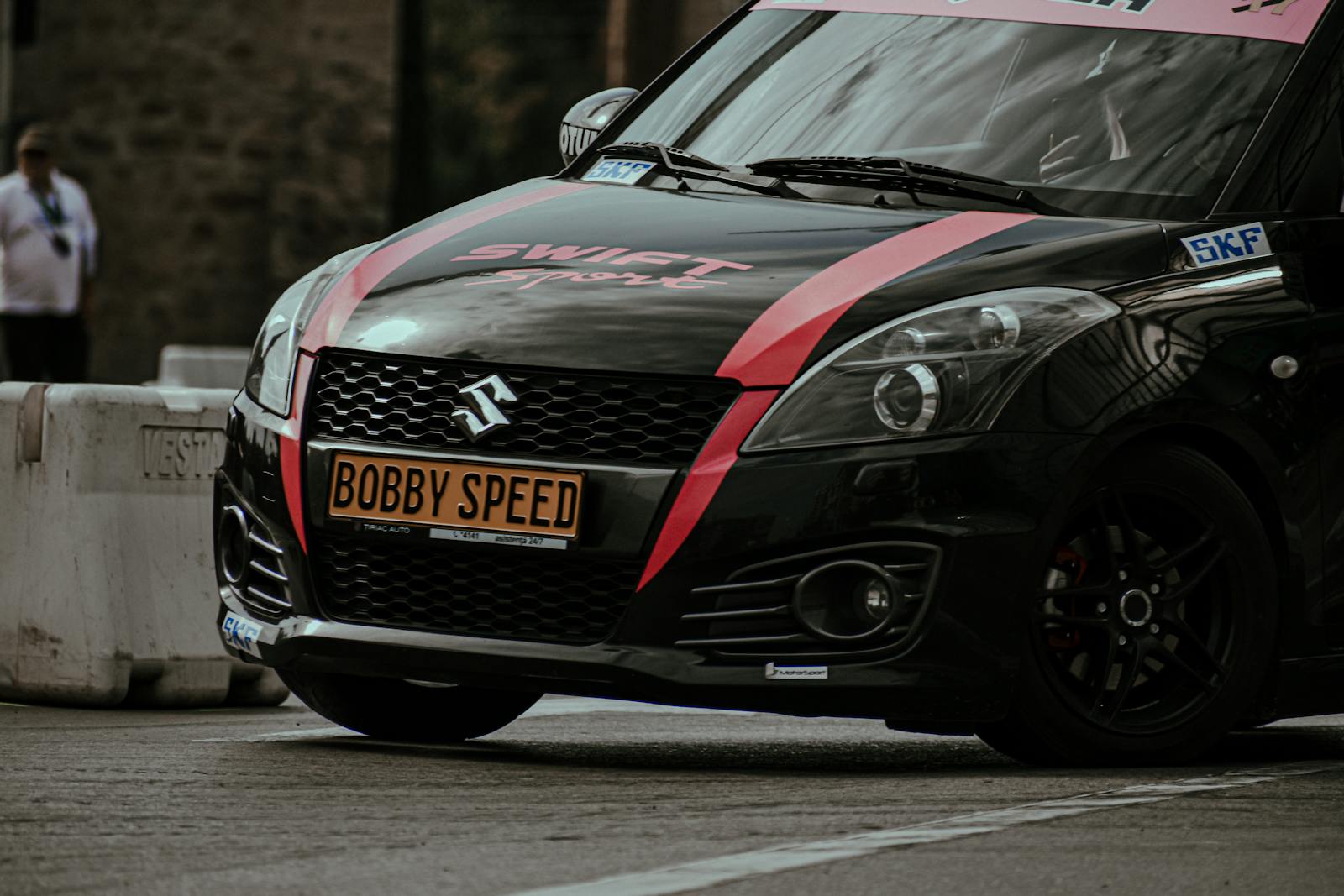 Black modern car with stickers driving on paved route during rally race in city