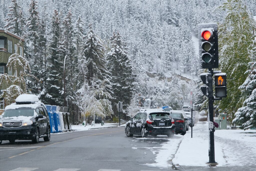 Traffic light on a snowy street with cars.