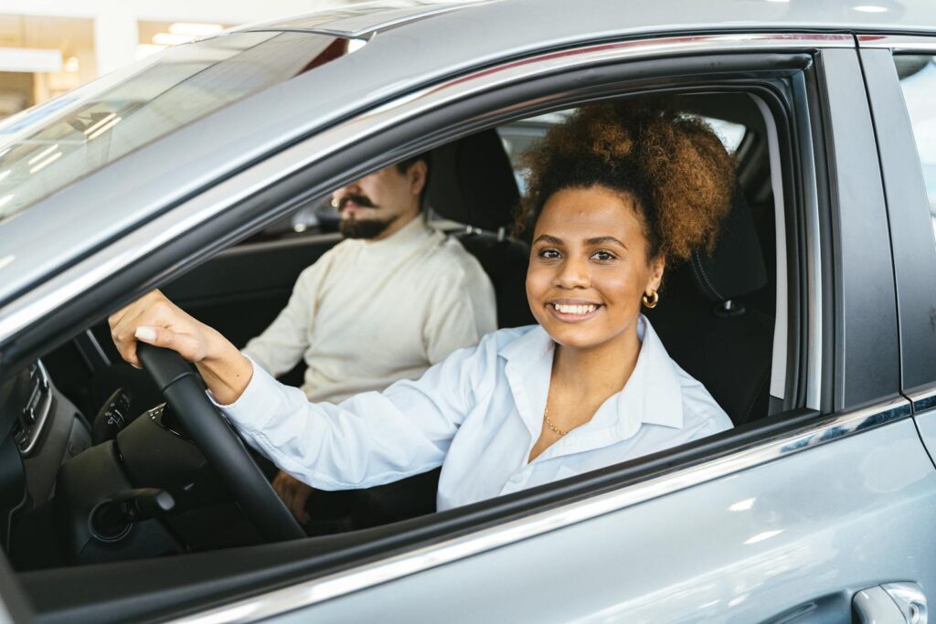 African American woman happily test driving a new car at a dealership. Capturing her joyful expression.