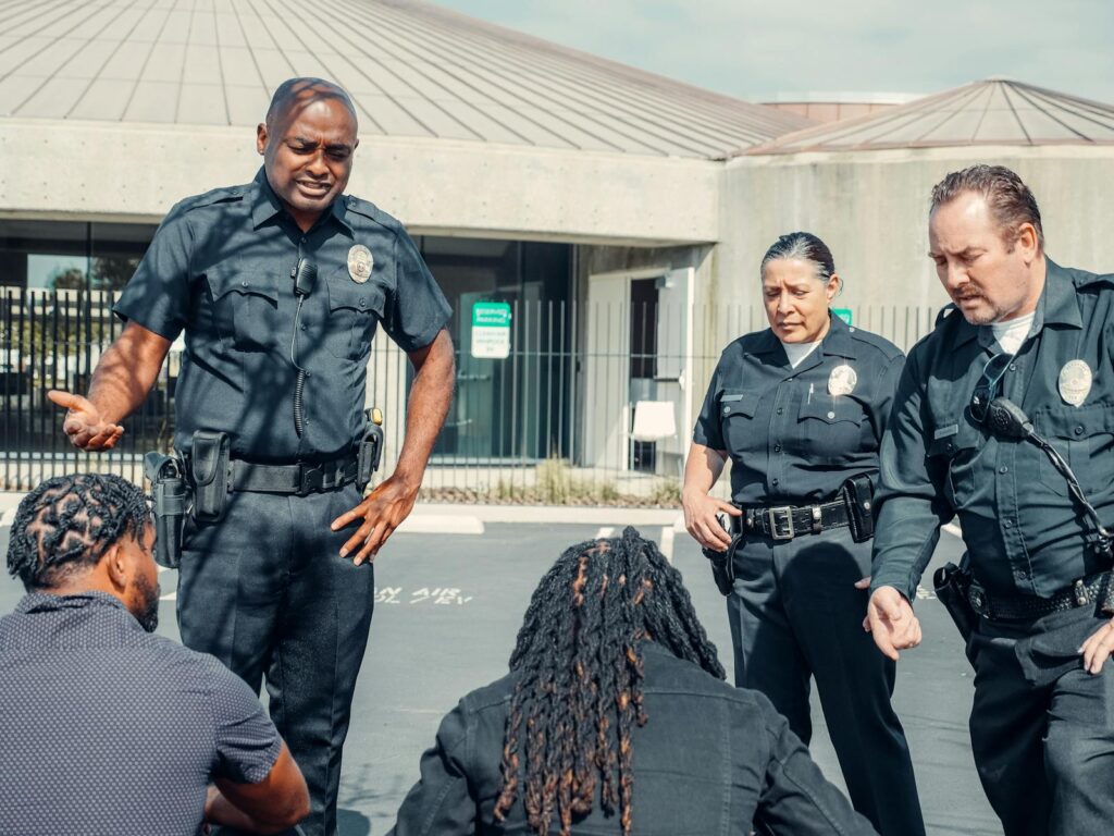 A group of police officers interact with civilians in a public outdoor setting.