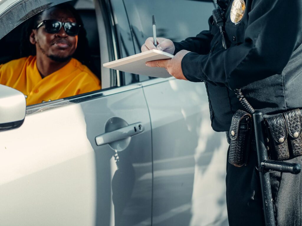 A police officer writes a ticket for a driver in a car during a roadside stop.