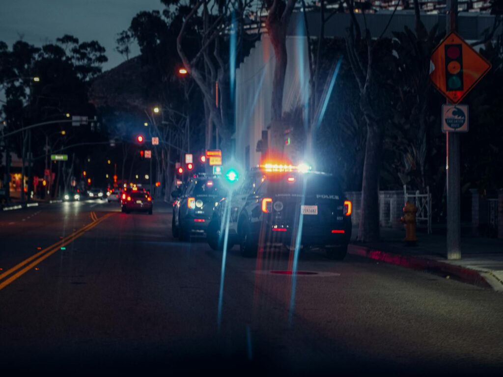 Illuminated police cars parked on a city street at night, creating a dramatic urban scene.
