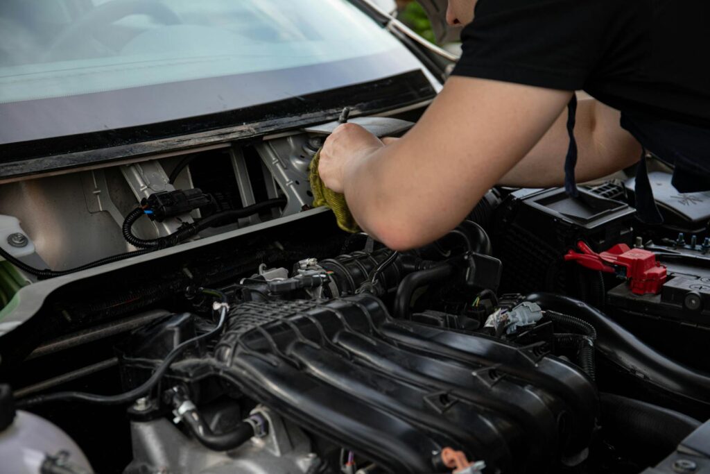 A close-up of a mechanic working on a car engine in a modern auto repair shop.