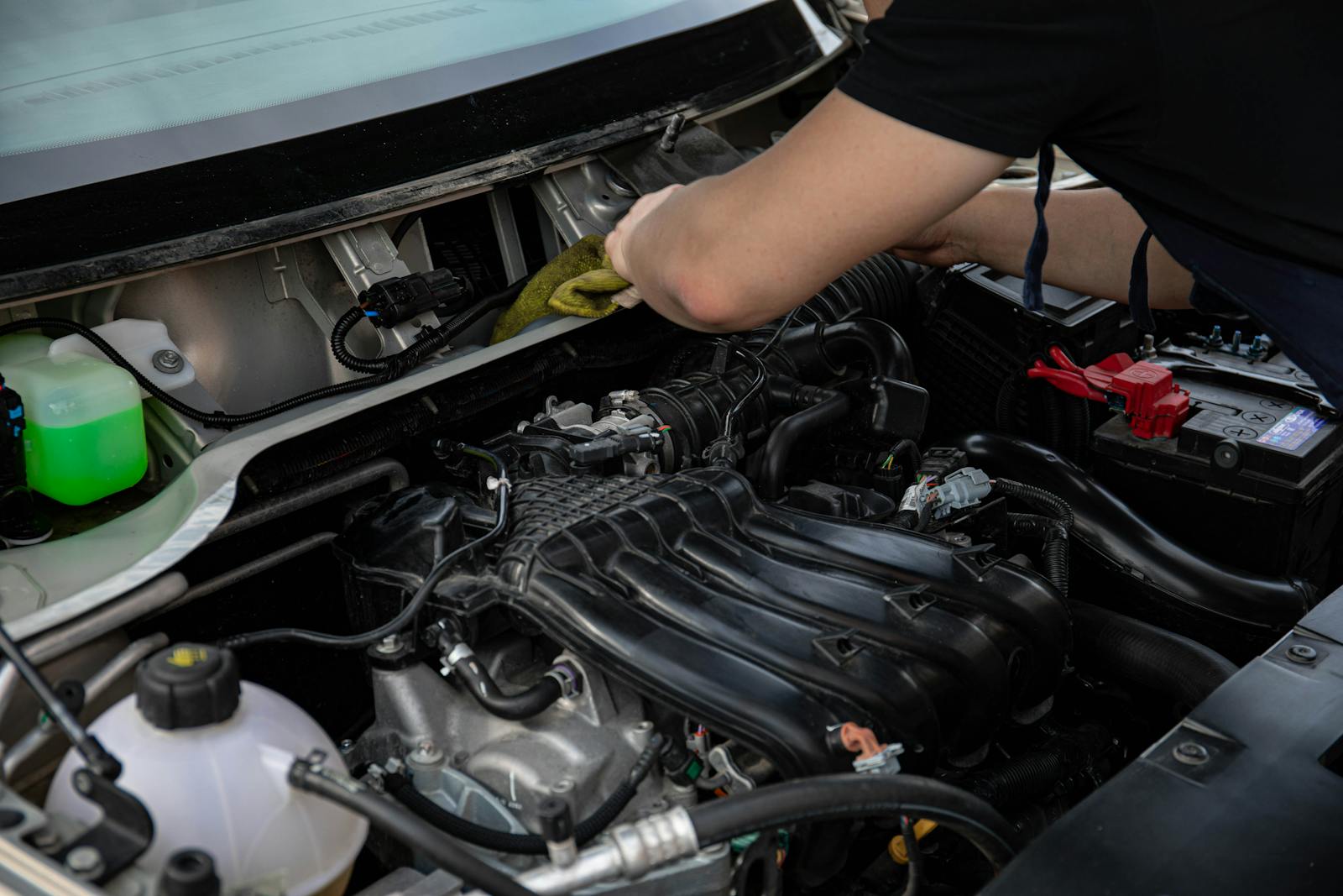 Close-up of a mechanic working on a car engine in a workshop setting.