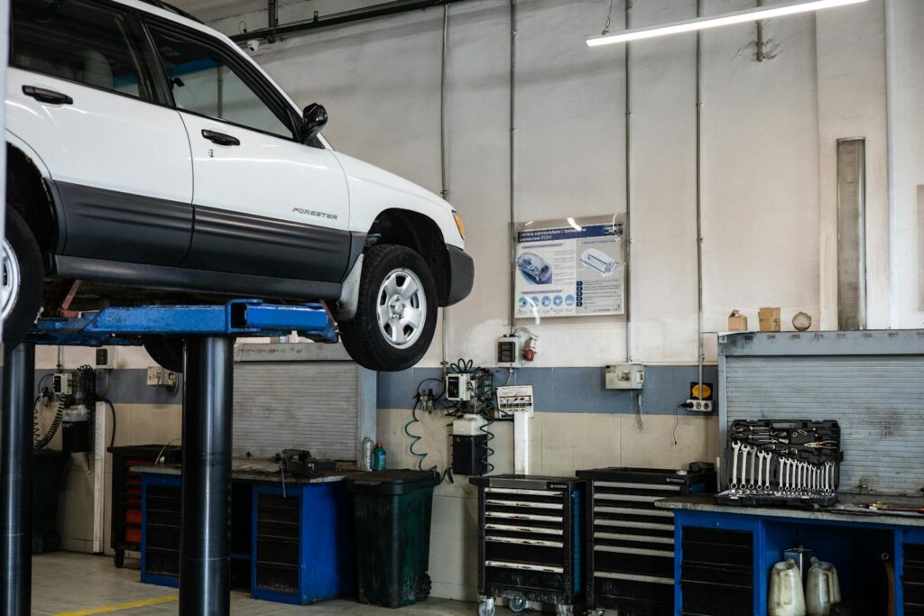 A car is elevated on a lift in a modern automotive repair shop, showcasing tools and equipment.