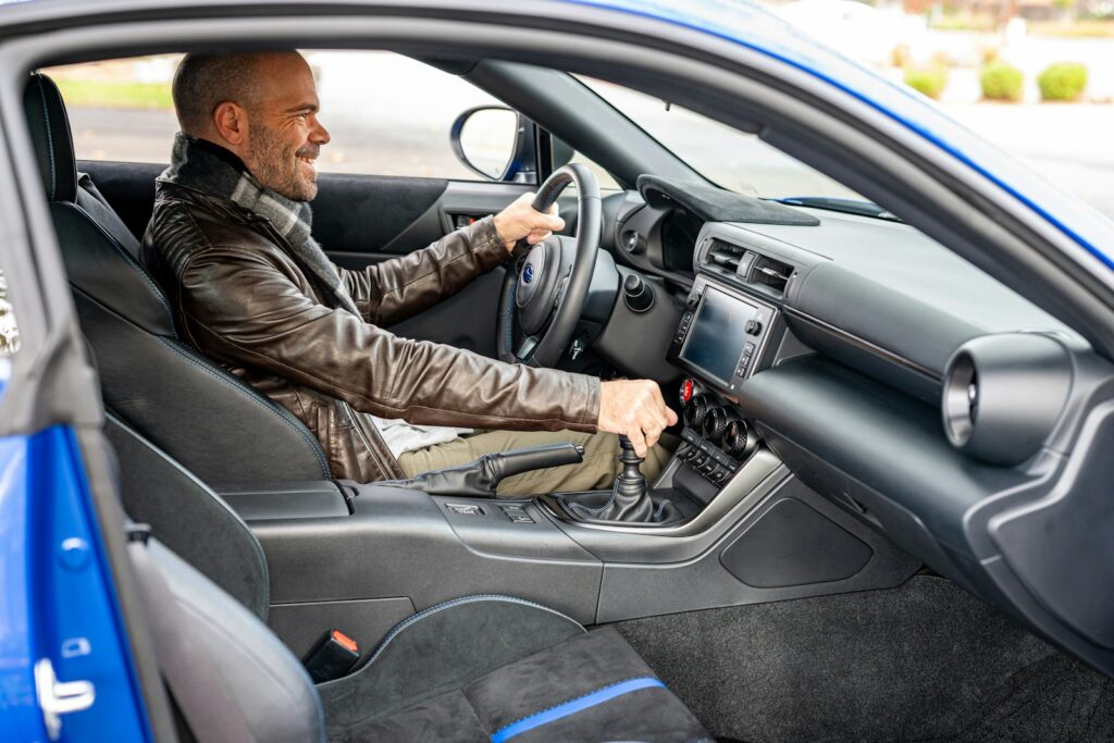 A man sitting in a car with a steering wheel