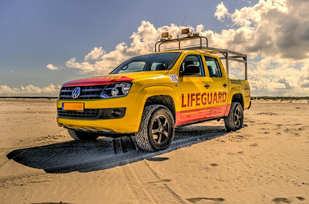 A vibrant yellow lifeguard vehicle parked on a sunny beach, ensuring safety for beachgoers.