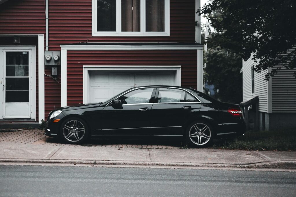 Elegant black car parked in front of a red residential house, showcasing urban lifestyle.
