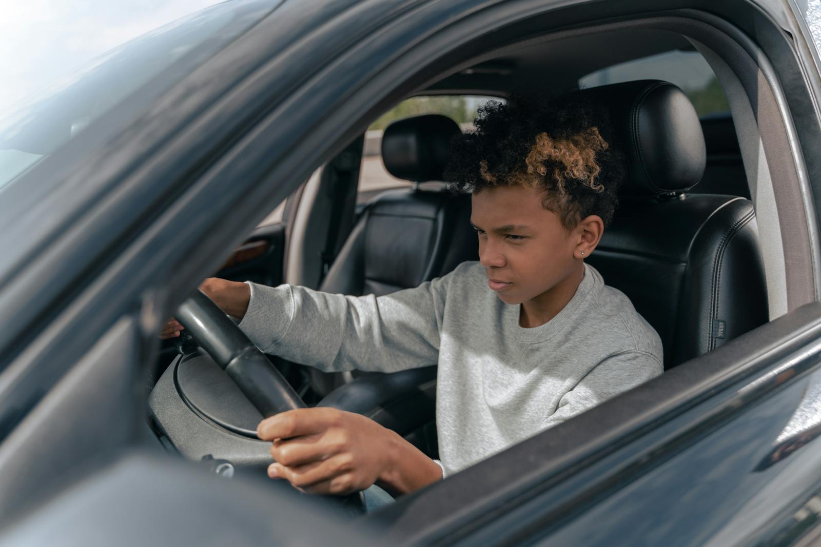 Teen boy learning to drive a car with focus and determination.