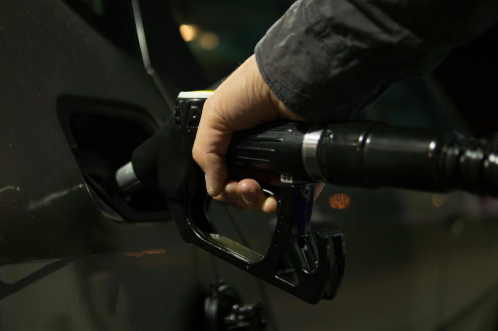 Close-up of a person refueling a car at a gas pump during night.