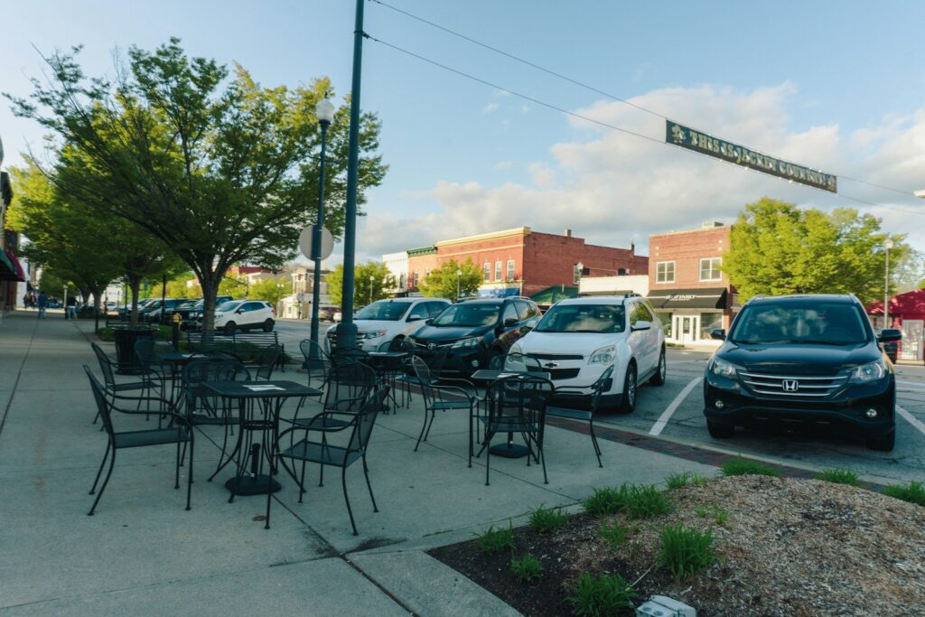 Outdoor seating area with parked cars and buildings.