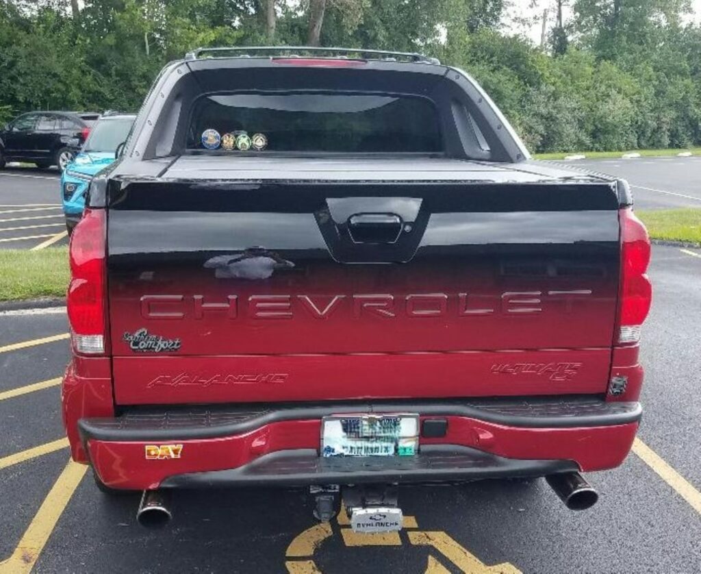 Here is a caption for the image: red chevrolet avalanche truck is seen from behind.