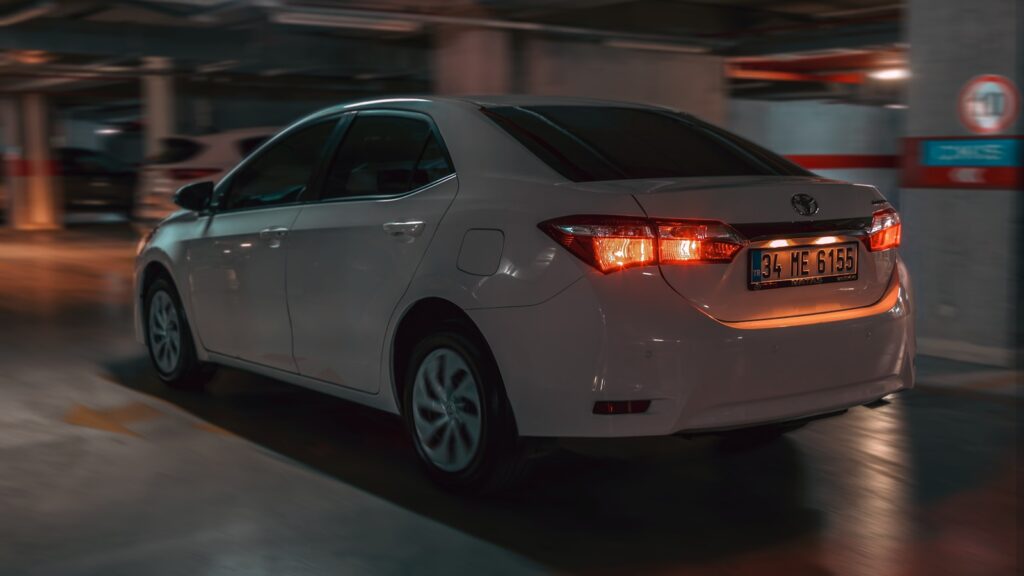 A white car is leaving a parking garage.