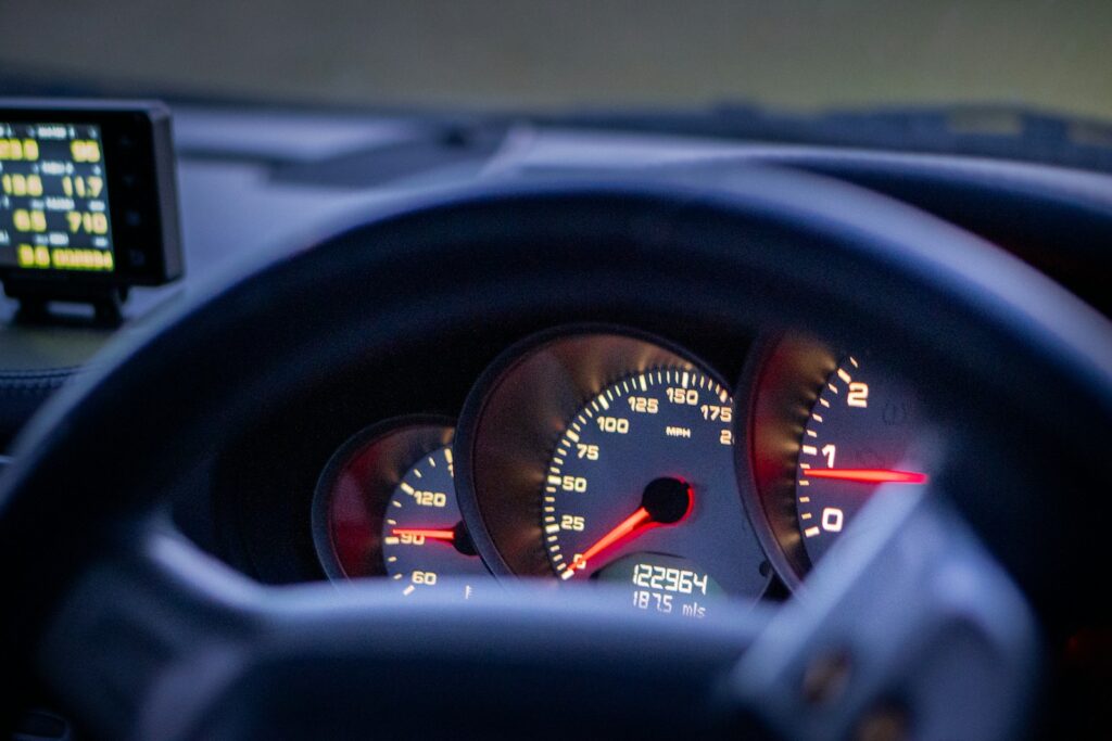 Car dashboard gauges and steering wheel are shown.