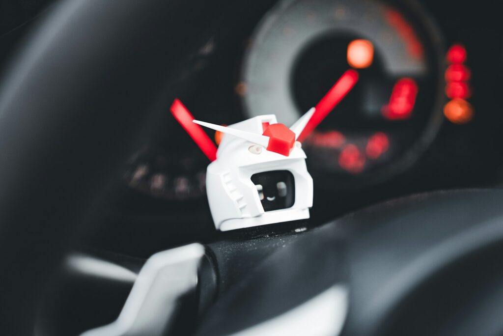 A gundam head sits on a car steering wheel.