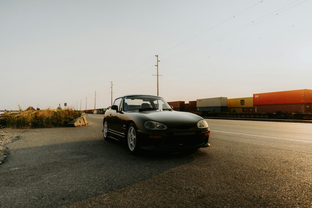 A car driving down a road next to a train