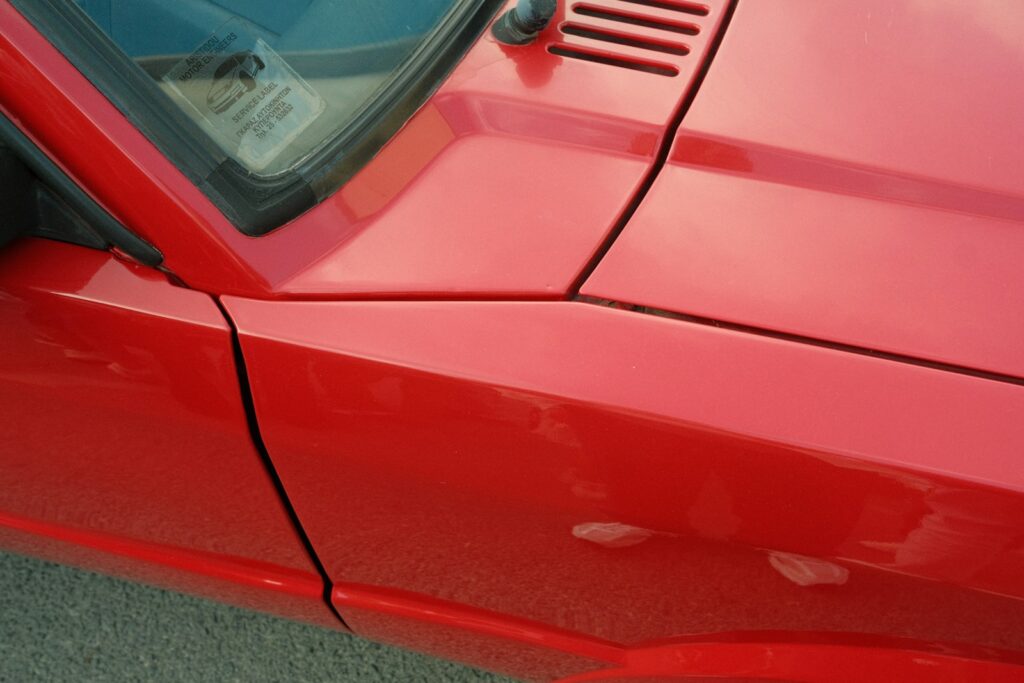 Close-up of a shiny red car's fender and hood.