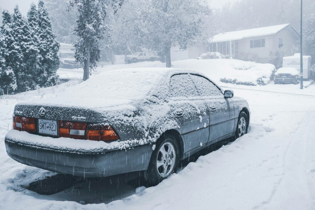 A car covered in snow on a street.