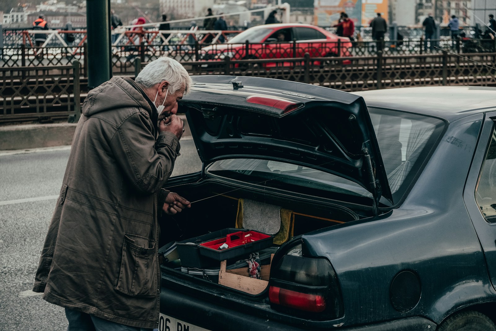 man in gray jacket standing beside black car during daytime