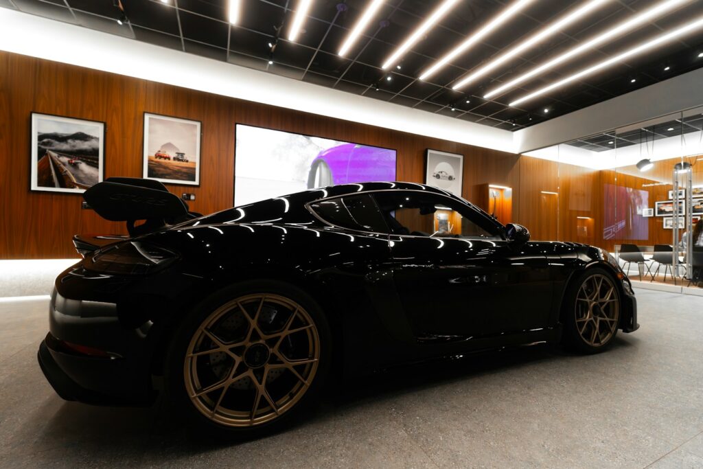 Sleek black sports car with gold wheels indoors.