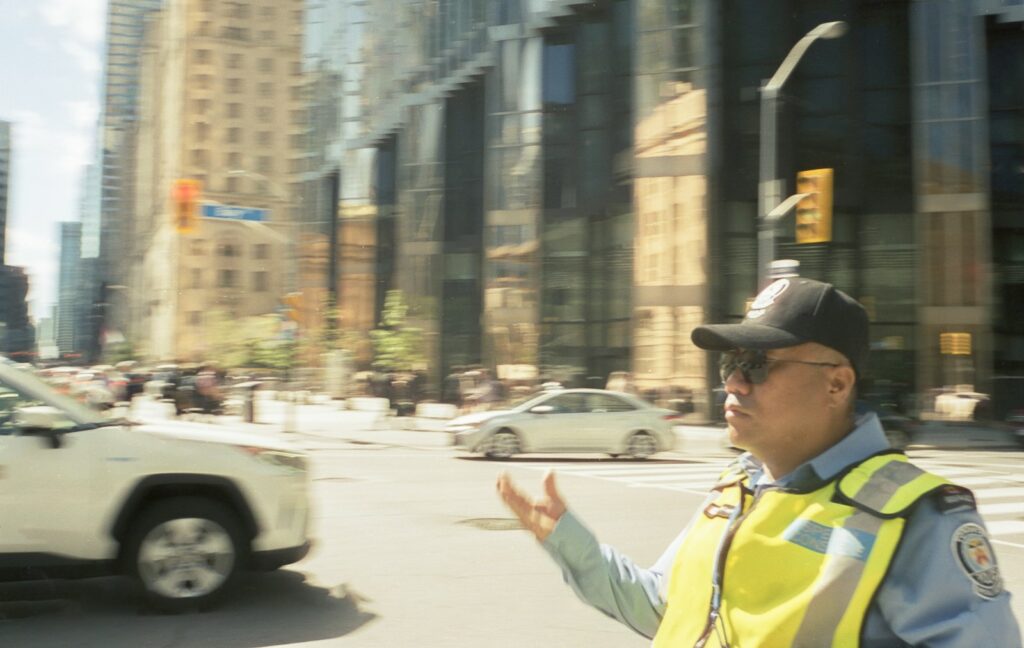 Man in safety vest directing traffic on city street.