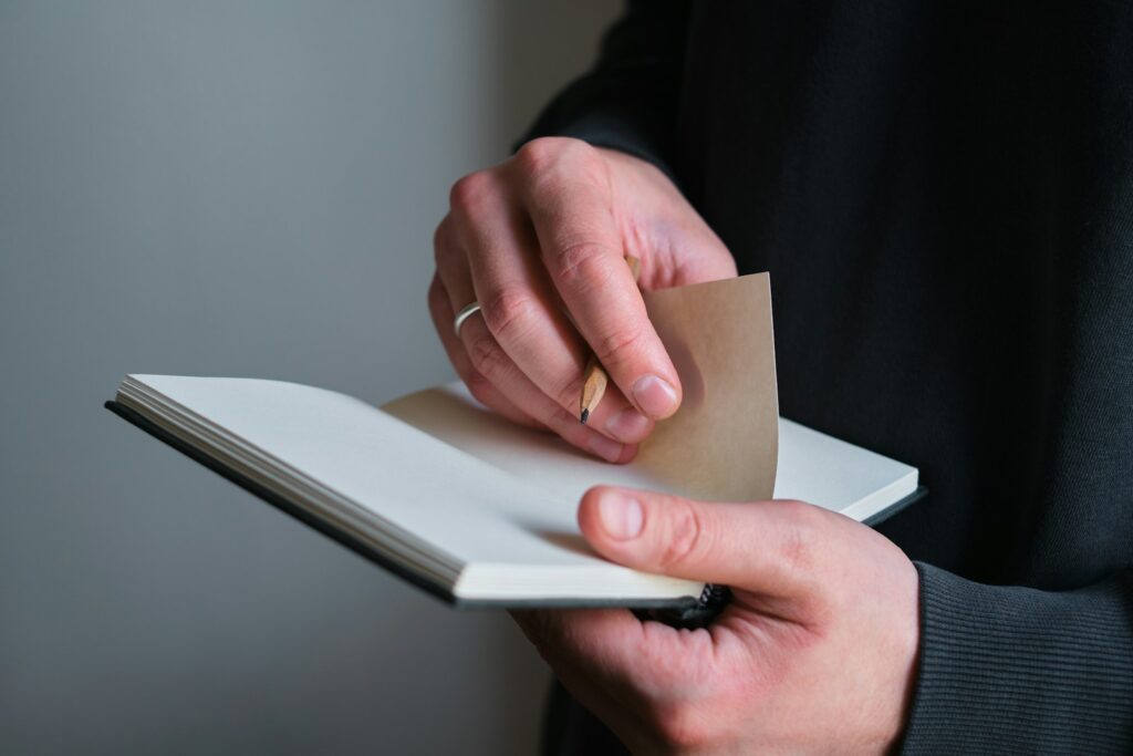 Hands holding a notebook and pencil