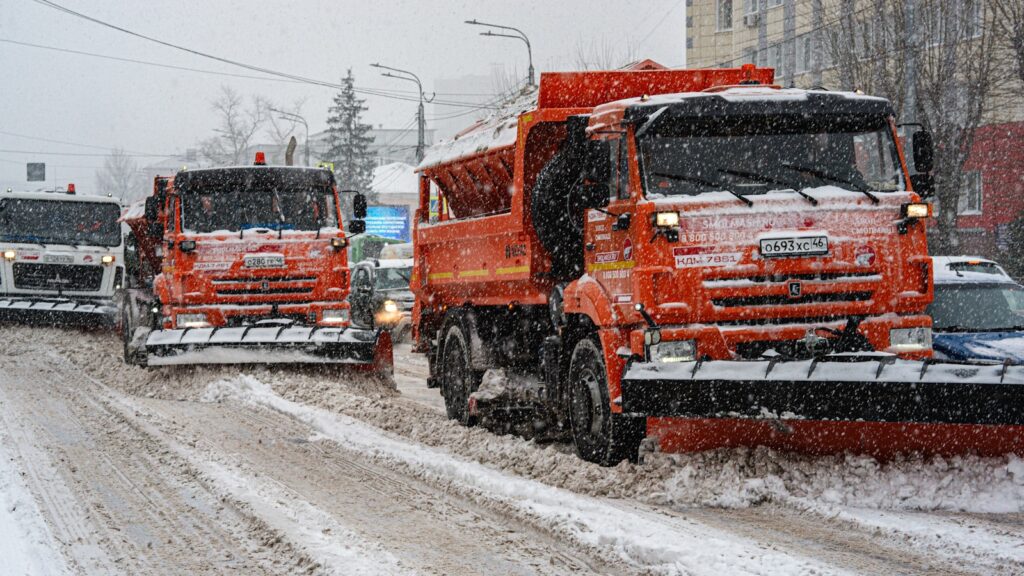 a couple of trucks driving down a snow covered road
