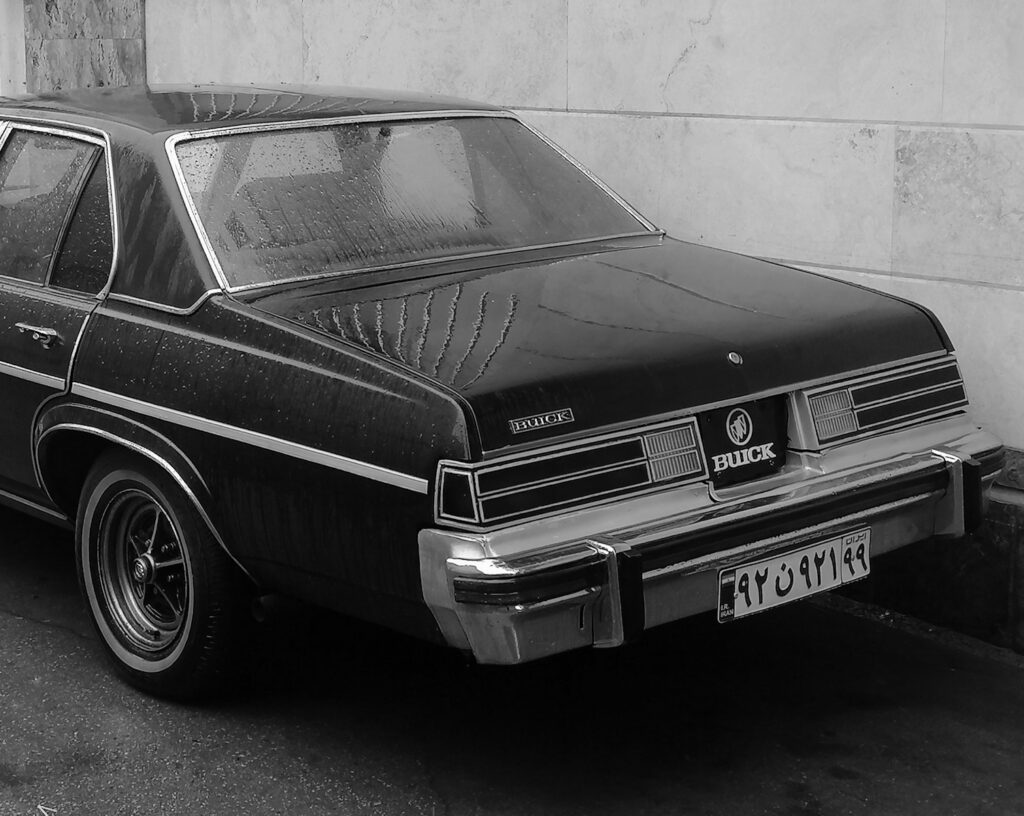 a black and white photo of a car parked in front of a building
