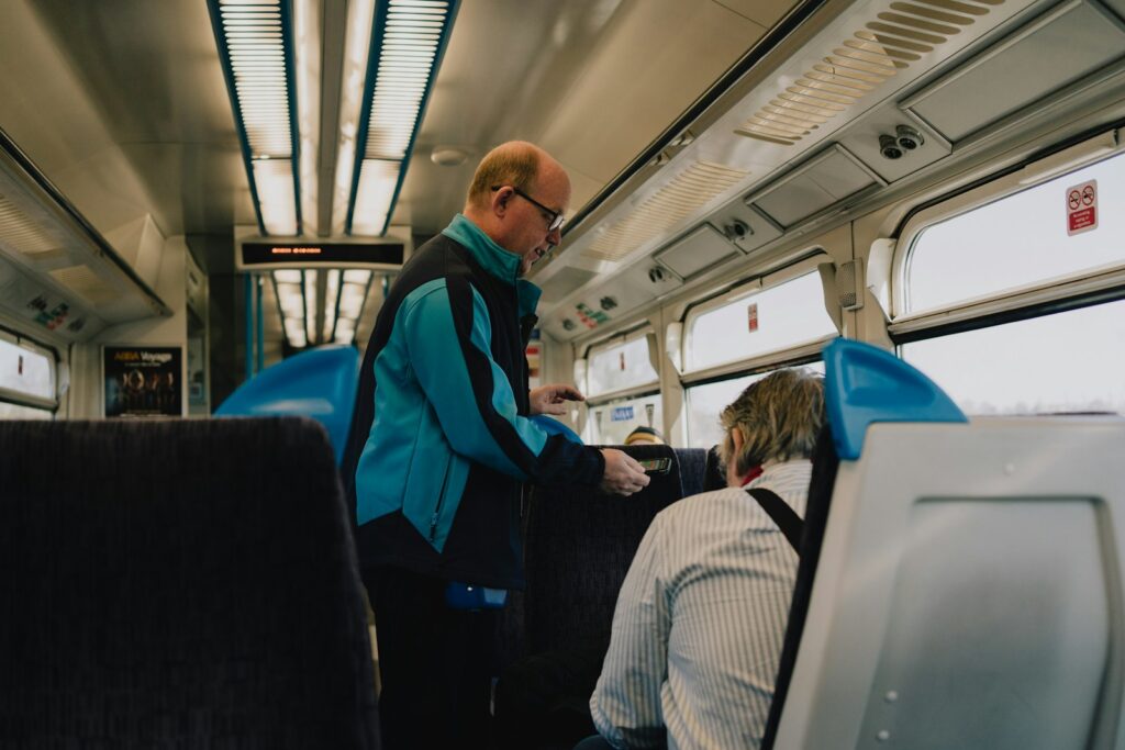 A man interacts with a passenger on a train.