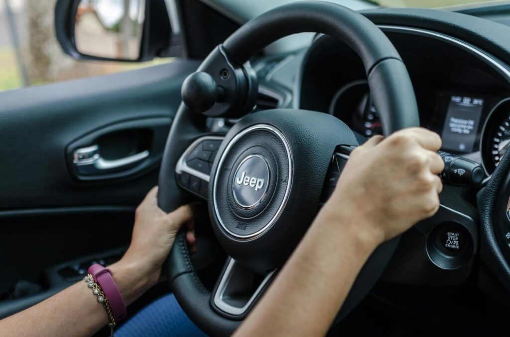 Detailed shot of hands holding a Jeep steering wheel during a drive.