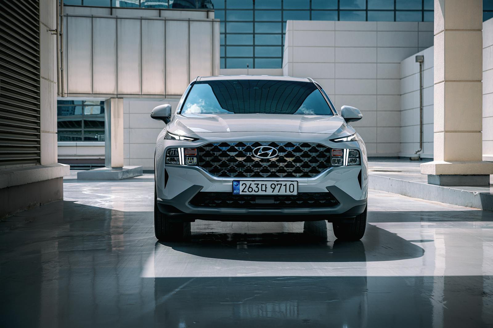Front view of a white Hyundai Santa Fe SUV parked in an urban setting with sleek architecture.