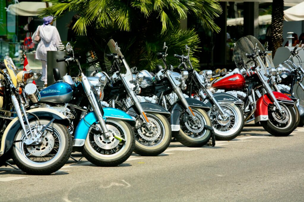 A lineup of stylish motorcycles parked under palm trees in a sunny city.